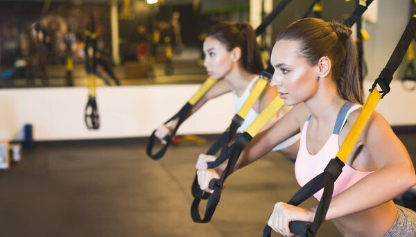 TRX training. Girls training triceps with fitness straps