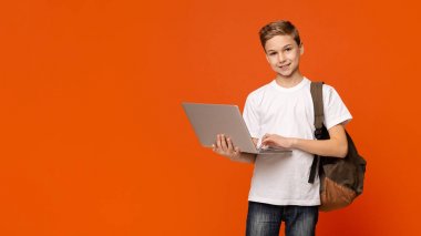 Dizüstü bilgisayar, turuncu arka plan kullanarak sırt çantası ile Genç çocuk