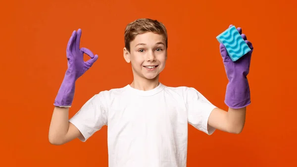 Cute boy in cleaning gloves showing OK sign and holding sponge — Stock Photo, Image