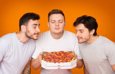 Üç Erkek Turuncu Arka Plan Üzerinde Sıcak Pizza Kokulu