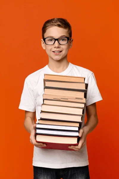 Söt flitig elev pojke i glas med hög med böcker — Stockfoto