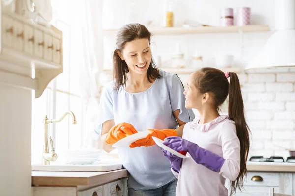 Helpende hand. Schattig tiener meisje helpt haar moeder in het wassen van gerechten in familie keuken — Stockfoto