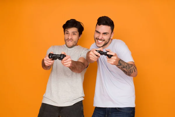 Two Friends Playing Video Games Over Orange Background