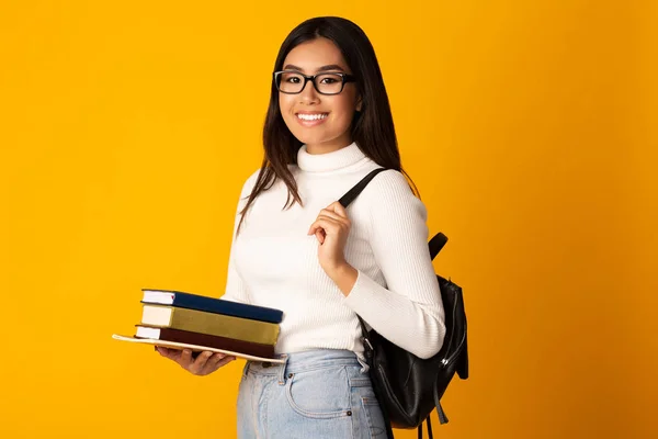 Aziatische student meisje met boeken en rugzak, gele achtergrond — Stockfoto