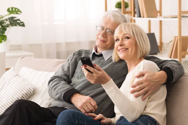 Šťastný starší pár objímající a pozorují televizi — Stock fotografie