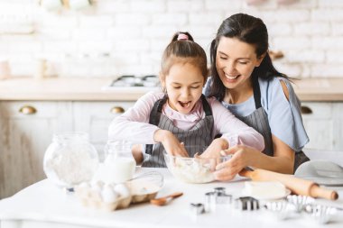 Anne ve kızı pasta yapmak için hamur hazırlanıyor