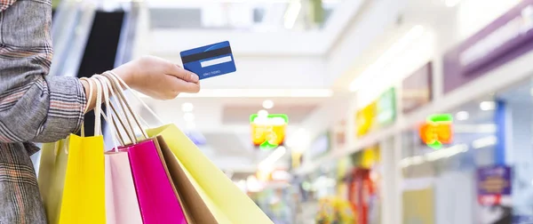 Mujer sosteniendo tarjeta de crédito y llevando bolsas de papel — Foto de Stock