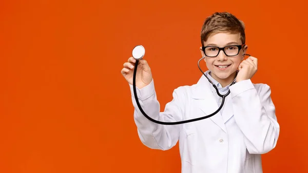 Niño sonriente en uniforme médico jugando con estetoscopio — Foto de Stock