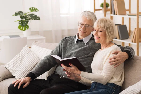 Liebendes Seniorenpaar liest gemeinsam Buch im Wohnzimmer — Stockfoto