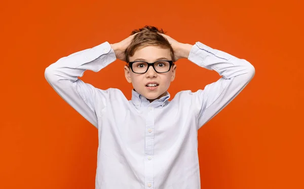 Шокований хлопчик-підліток в окулярах торкається голови з подивом — стокове фото