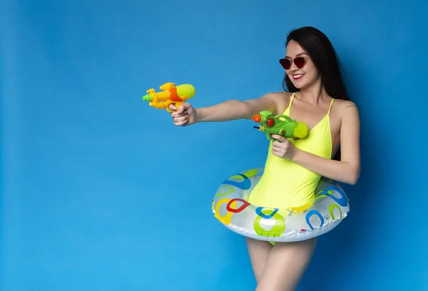Verspieltes Mädchen im Badeanzug schießt mit Wasserpistolen auf freien Platz — Stockfoto