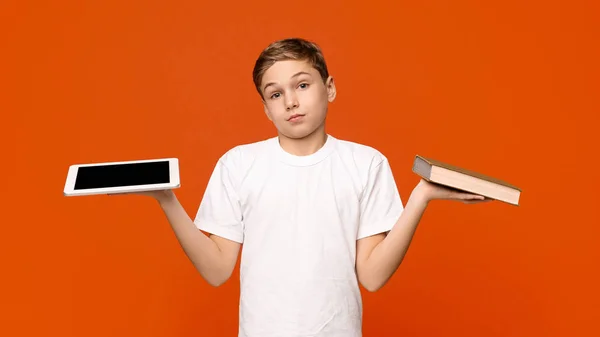 Nastoletni dzieciak wybierać pomiędzy tabletem a książką — Zdjęcie stockowe