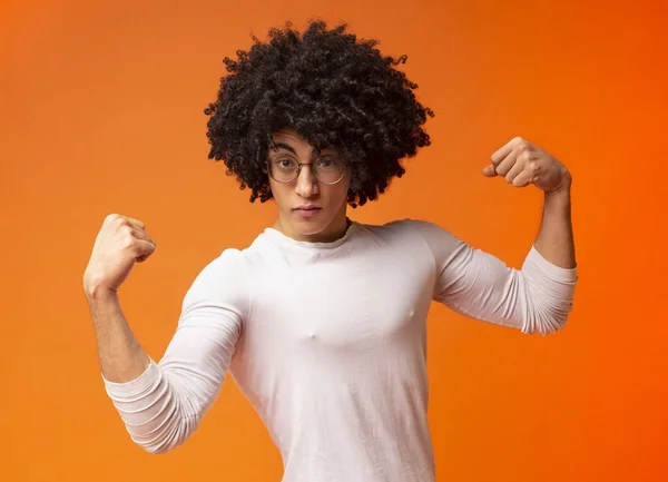 Impresionante chico negro fuerte mostrando bíceps sobre fondo naranja — Foto de Stock