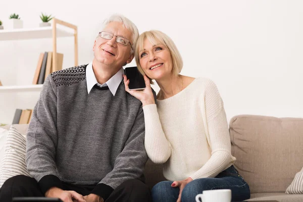 Gespräche mit Verwandten. Seniorenpaar teilt Telefon — Stockfoto