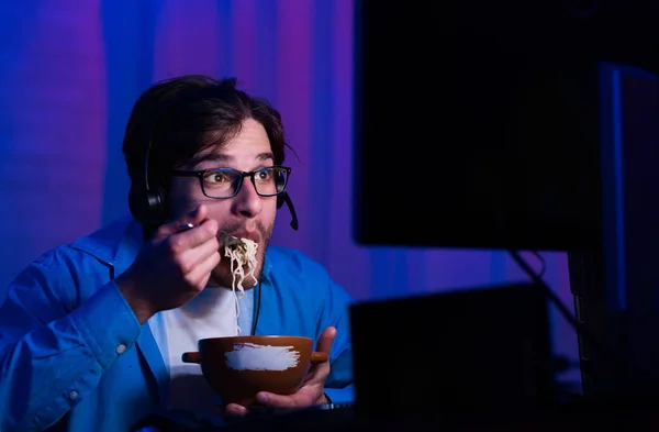 Gamer comer macarrão, jogando jogos de vídeo online — Fotografia de Stock