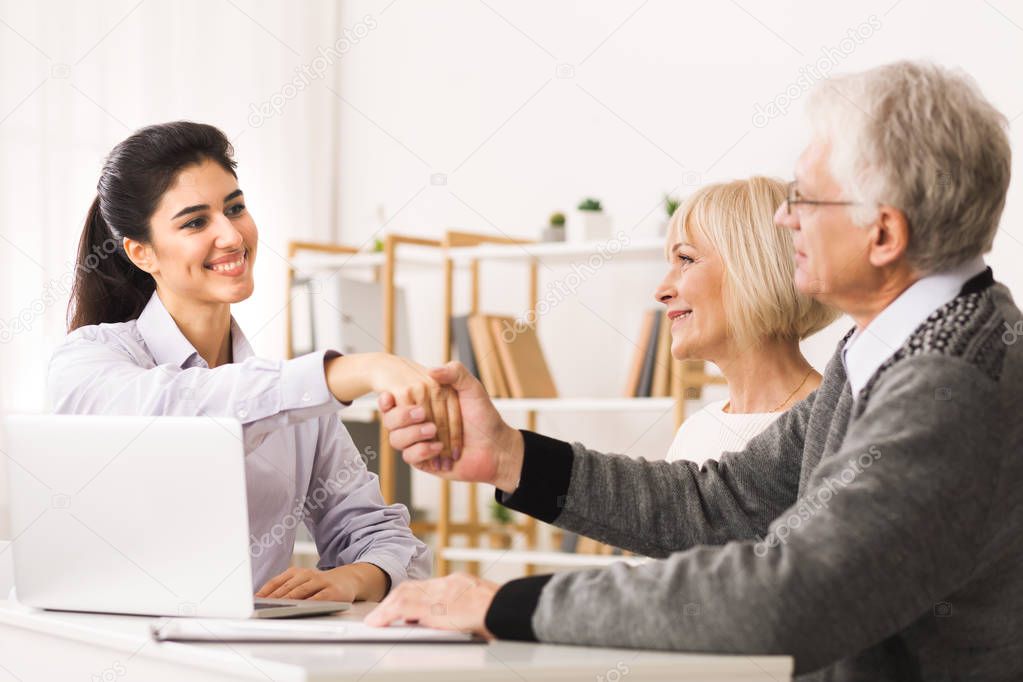 Happy Mature Couple Sealing Contract With Financial Advisor