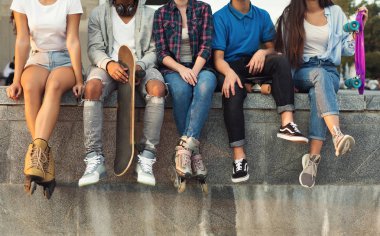 Active diverse friends sitting in urban skatepark with skateboards clipart