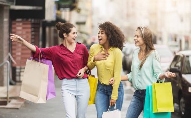Sokakta alışveriş torbalarıyla yürüyen genç kadınlar