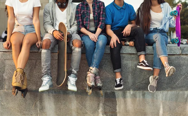 Amigos activos y diversos sentados en skatepark urbano con skateboards — Foto de Stock