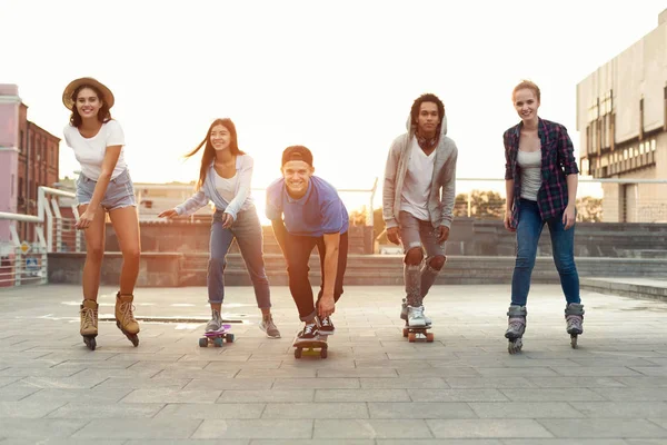 Šťastní Teenageři se baví, jezdí na skateboarcích a kolečcích — Stock fotografie