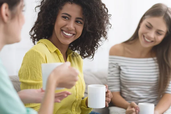 Счастливые девушки пьют кофе и разговаривают в гостиной — стоковое фото