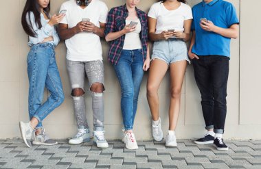 Kentsel arka planda akıllı telefon kullanan çok kültürlü arkadaş grubu