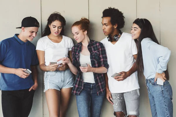 Menina adolescente mostrando piada no telefone para diversos amigos — Fotografia de Stock