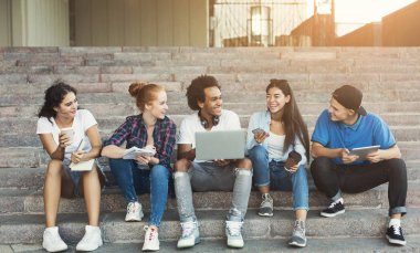 Kampüs merdivenlerinde oturan neşeli gençler grubu