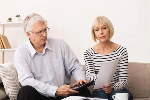 Besorgtes Senioren-Paar prüft seine Rechnungen zu Hause — Stockfoto