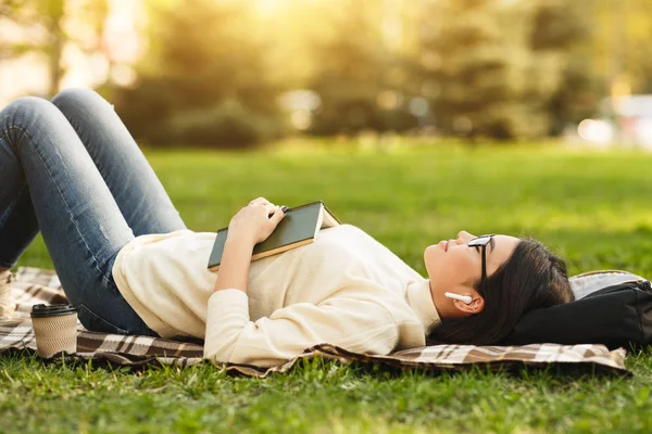Студентська дівчина бреше з відкритою книгою і спить на ковдрі — стокове фото