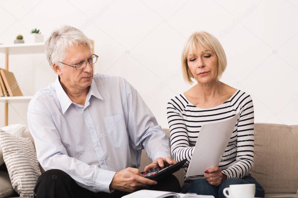 Worried Senior Couple Checking Their Bills At Home
