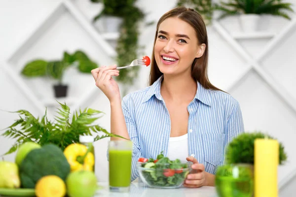 Lycklig kvinna äter hälsosam sallad, sitter i köket — Stockfoto