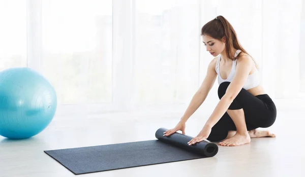 Jong yoga vrouw rollen haar mat na training — Stockfoto
