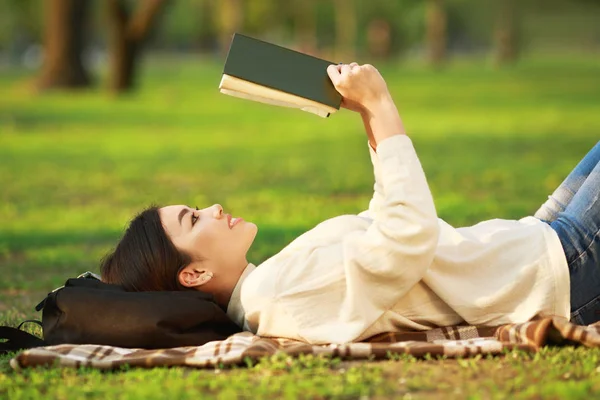 Kniha pro čtení dívek ležící na trávě, pohled z boku — Stock fotografie