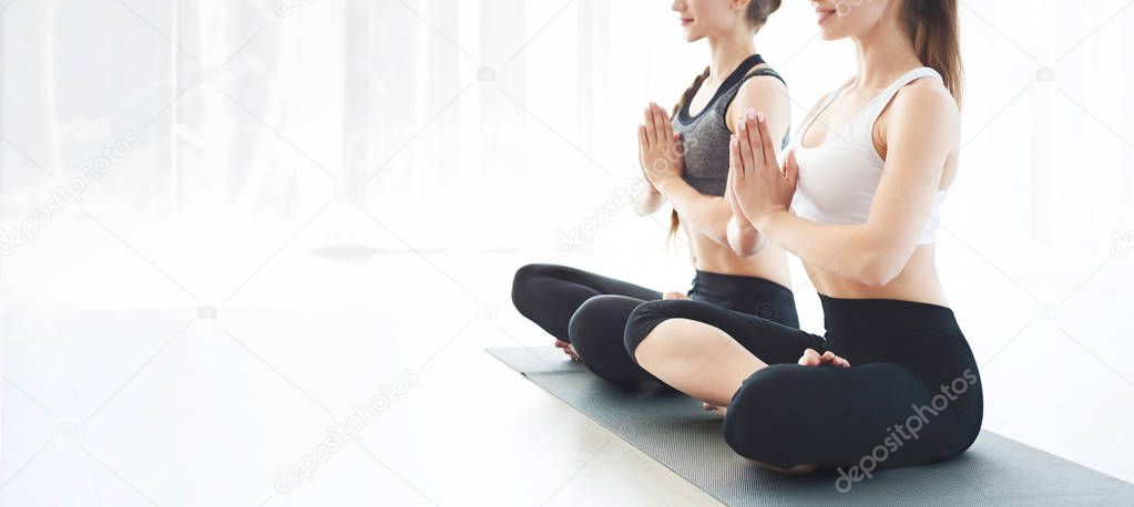 Two young women in yoga class making exercises