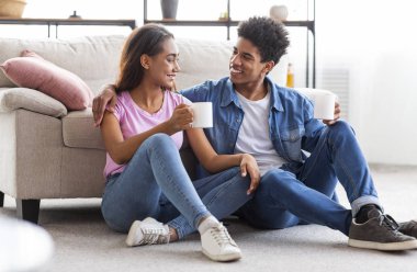 Mutlu genç çift konuşurken ve yerde oturan kahve içme