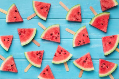 Ahşap çubuklar üzerinde dilimlenmiş sulu meyve, mavi arka plan