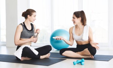 Beyaz arka plan üzerinde yoga sınıfından sonra konuşan iki genç kız