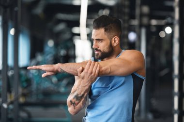 Spor salonunda sportif adam eller için germe egzersizleri yapıyor