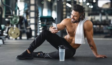 Spor salonunda cep telefonu kullanan kaslı adam, boş alan