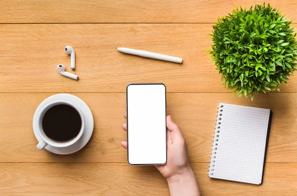 Mobiele telefoon met blanco scherm in vrouw hand op werkplek — Stockfoto