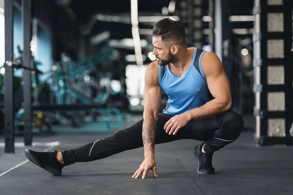 Sportieve man bij gym doen Stretching oefeningen voor benen — Stockfoto
