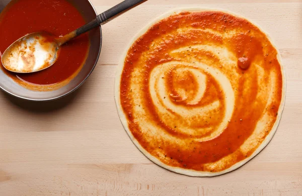 Preparação de pizza. Base crua da pizza com ketchup — Fotografia de Stock