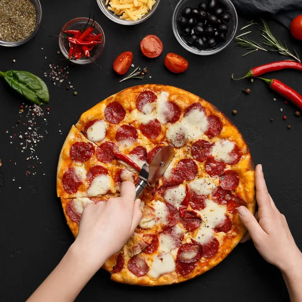 Frau schneidet Paprika-Pizza in Scheiben — Stockfoto