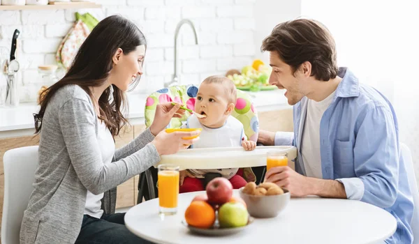 Gut aussehende junge Familie frühstückt zusammen mit ihrem Baby — Stockfoto