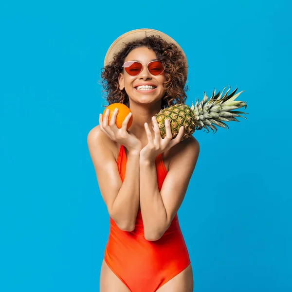 Chica negra feliz en traje de baño disfrutando de frutas frescas de verano —  Fotos de Stock