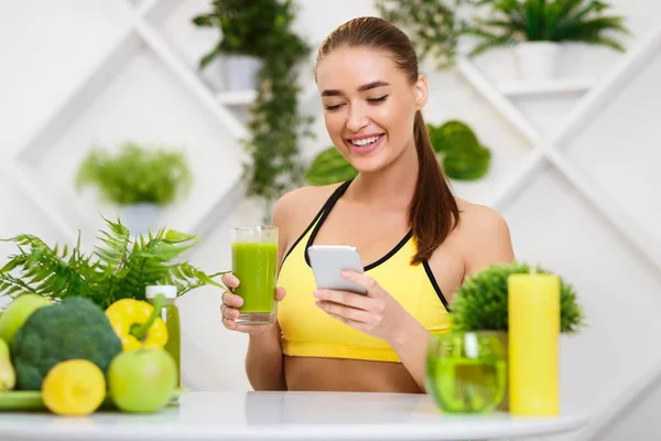 Menina bebendo suco de desintoxicação e mensagens de texto no telefone — Fotografia de Stock