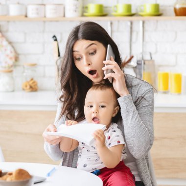 İş annesi telefonda konuşuyor ve bebek ellerinden notlar alıyor