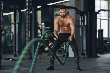 Fitness adamı spor salonunda halatlarla çalışıyor.