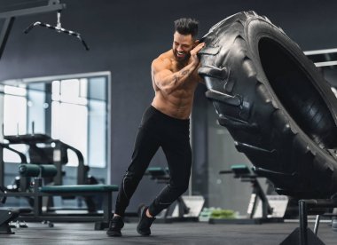 Çıplak adam spor salonunda büyük lastik çeviren